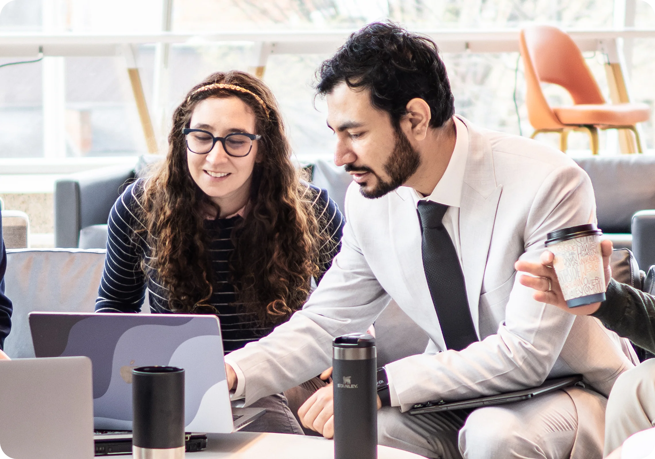 Two people looking at a laptop together at a table with coffee cups