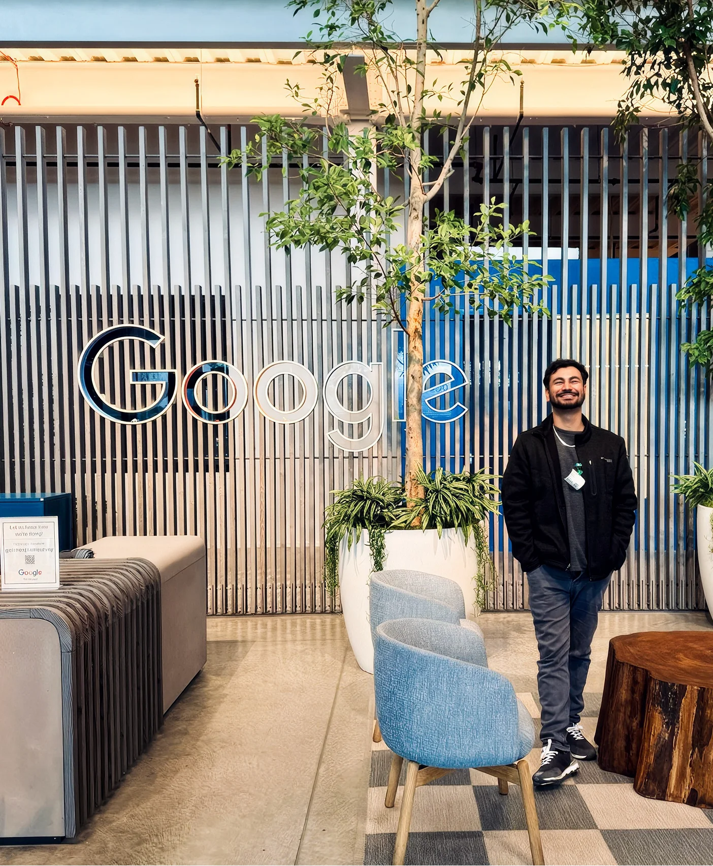 A man standing next to a large Google sign in an office lobby