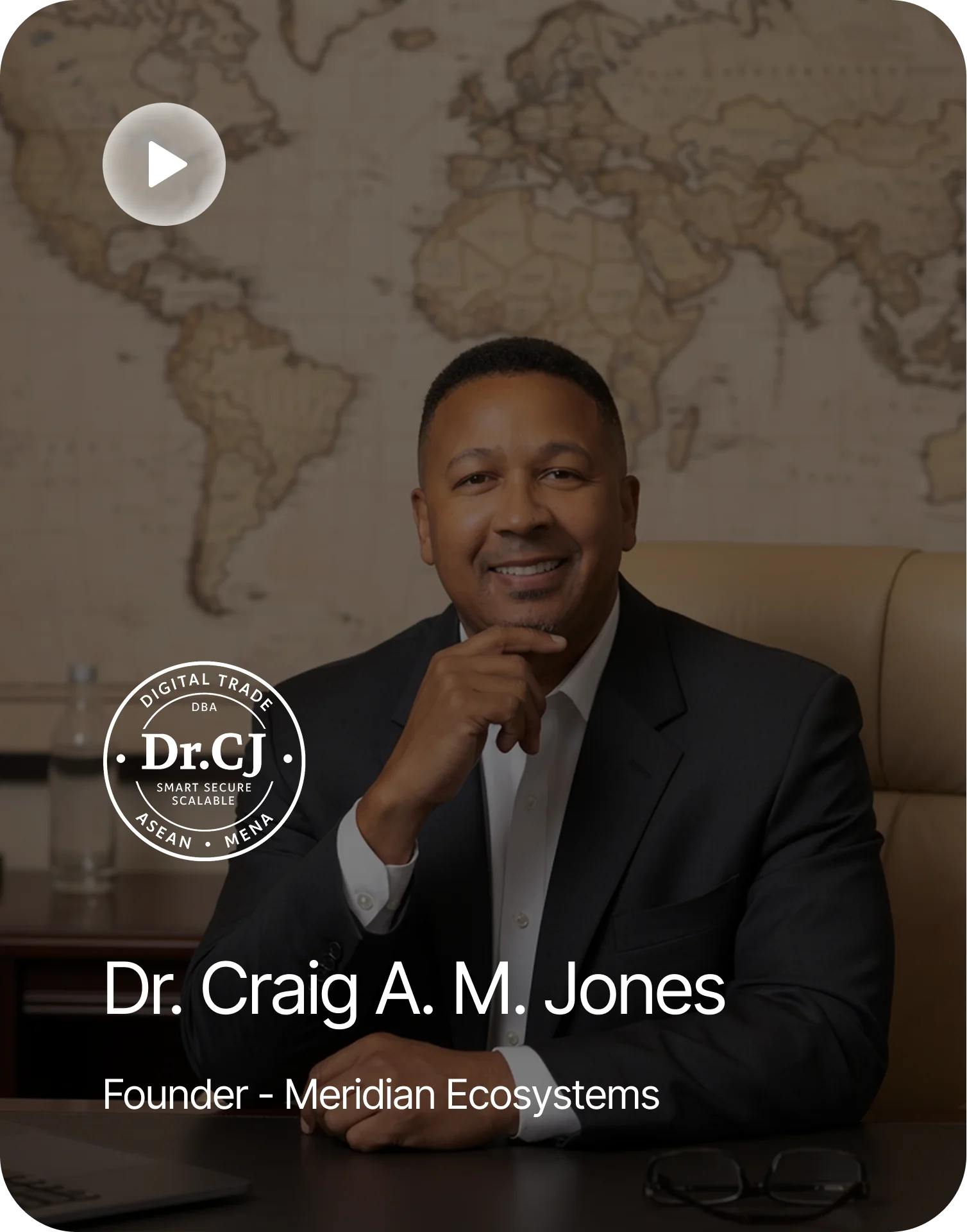 testimonials A man in a suit sitting at a table in front of a world map, with a video play button in the top left corner
