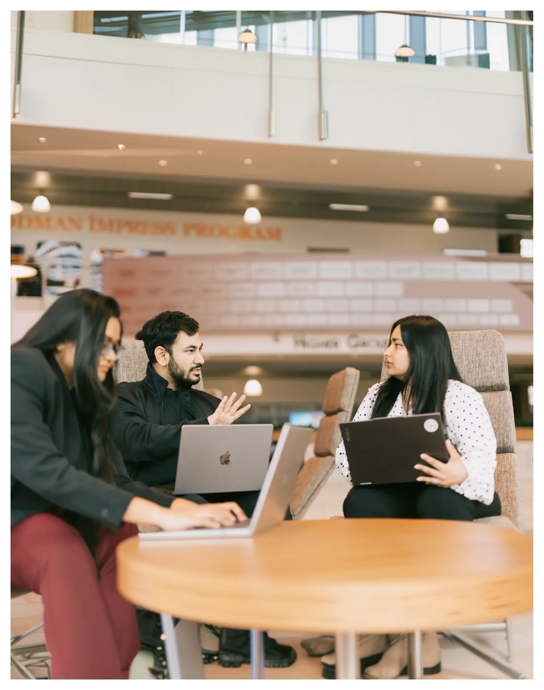 contact us A group of people sitting at a table with laptops, likely discussing or working on a project together