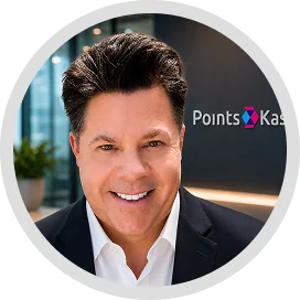 testimonials A man in a suit and white shirt smiling at the camera, with a plant in the background and a black wall behind