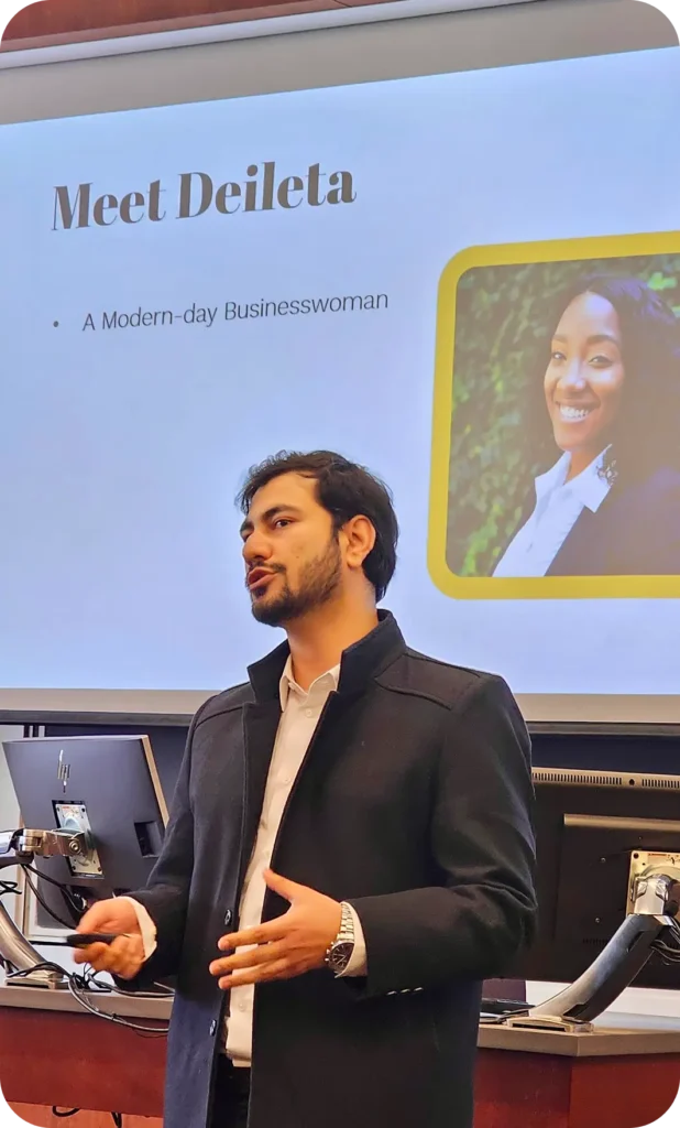 meeting A man in a black coat stands in front of a screen with a slide titled 'Meet Deileta' and a photo of a woman