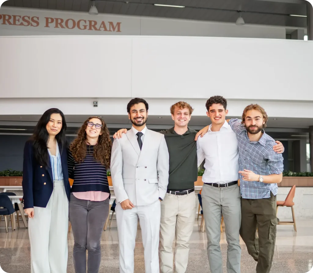 Six people standing together and smiling in a bright office atrium